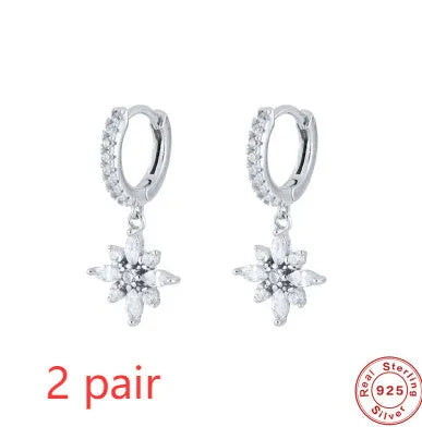 A pair of sterling silver snowflake pendant earrings with cubic zirconia stones on a white background.