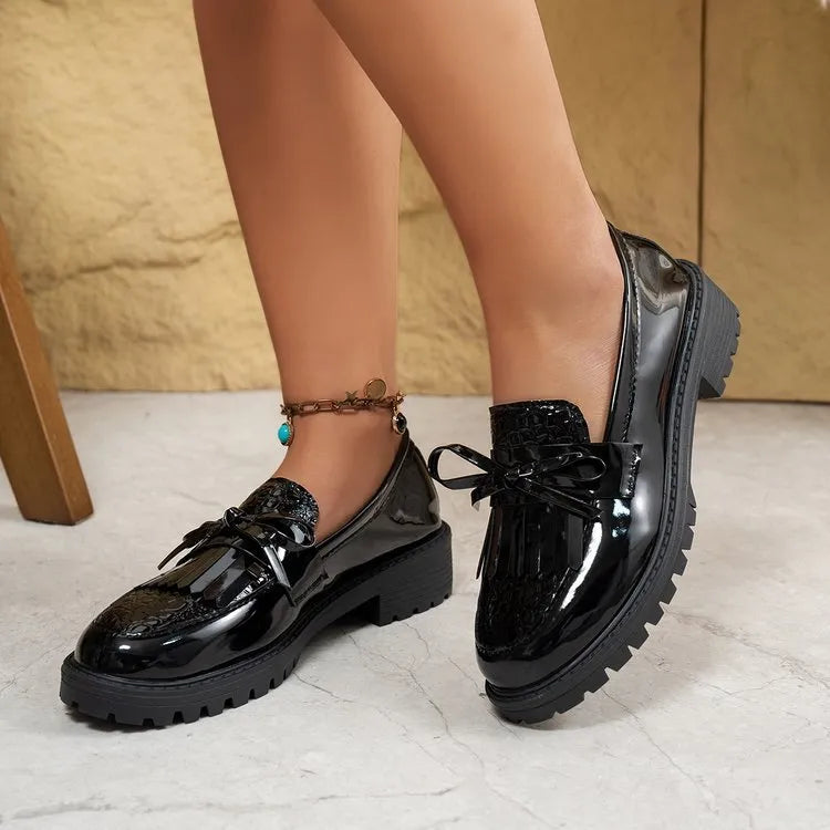 Women's black slip-on loafer shoe with a decorative bow on the front.