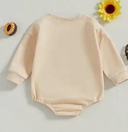 Apricot coloured infant jumpsuit with embroidered alphabet detailing and long sleeves