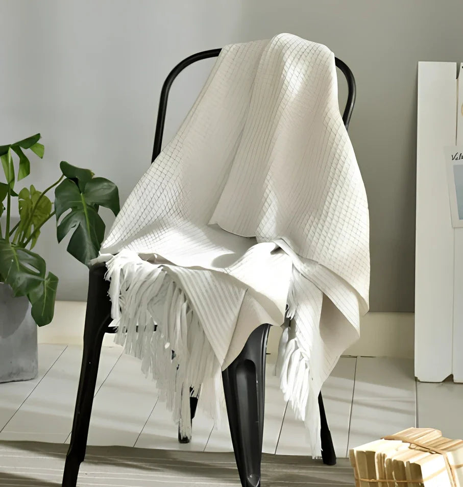 130x150cm knitted acrylic blanket with 10cm fringe detailing in beige colour draped over sofa