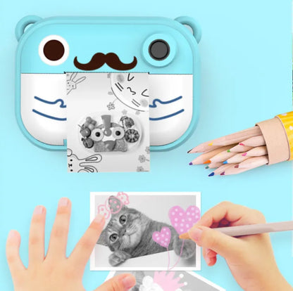 Pink instant print digital camera with LCD screen on a table next to printed photos and accessories.