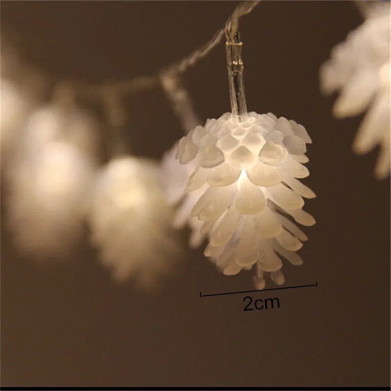 Warm white LED pine cone fairy light string on a green backdrop, showing plastic shell details.