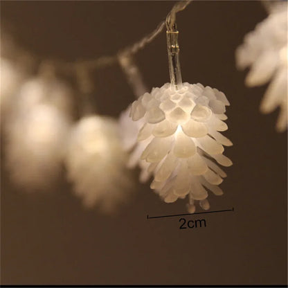 Warm white LED pine cone fairy light string on a green backdrop, showing plastic shell details.