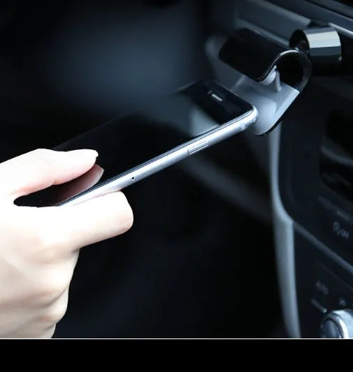 Black universal car phone holder with 360-degree rotating head mounted on a car air vent, holding a mobile phone.