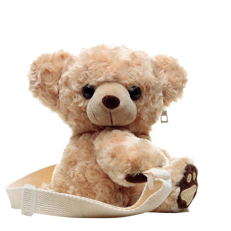 A plush teddy bear crossbody messenger bag with an adjustable shoulder strap and a zippered interior pocket for convenient storage.