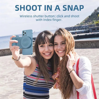 Black magnetic phone camera grip holder with rotatable stand on a table next to a smartphone.
