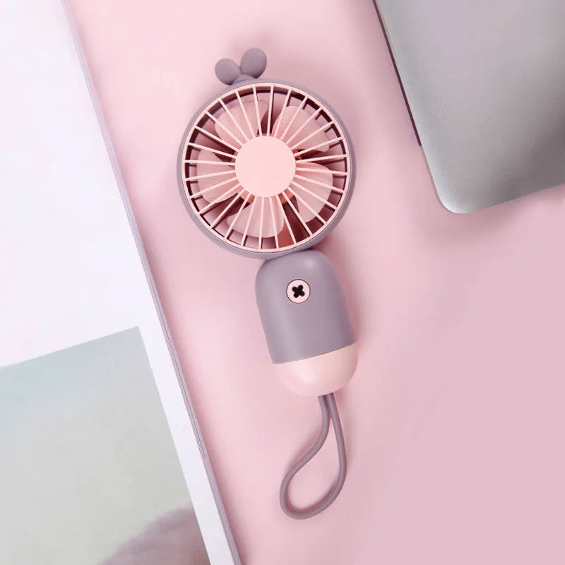 Handheld portable mini fan in green, pink, purple, or white, made from ABS and silicone with 500mAh battery