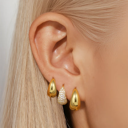 A pair of golden geometric clip-on earrings with a round design element on a white background.