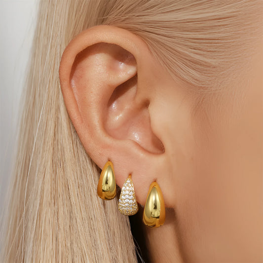 A pair of golden geometric clip-on earrings with a round design element on a white background.