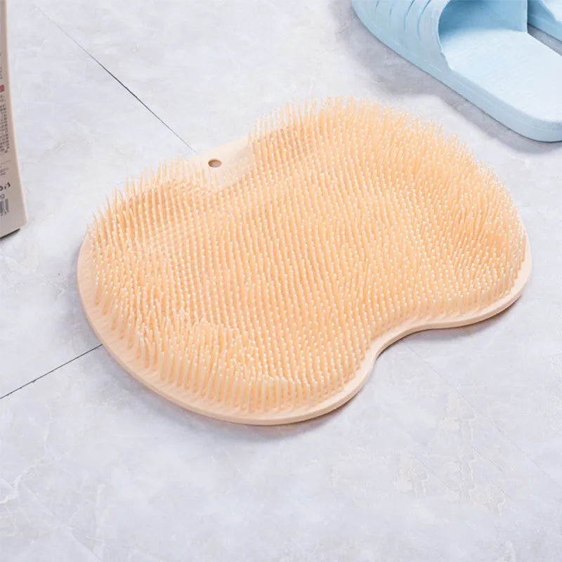 Orange non-slip massage bath brush with silicone bristles and suction cup base on shower floor