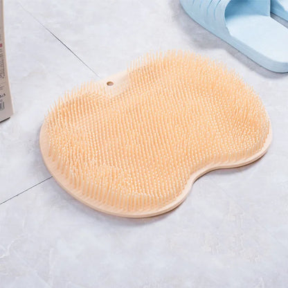 Orange non-slip massage bath brush with silicone bristles and suction cup base on shower floor