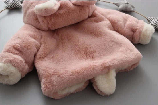 Baby wearing pink cotton coat with velvet accents, showing flocking fabric texture and cotton filling insulation