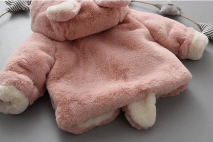 Baby wearing pink cotton coat with velvet accents, showing flocking fabric texture and cotton filling insulation