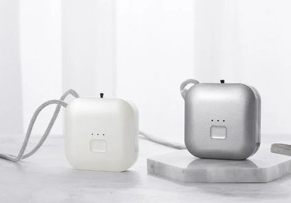 Pink wearable USB air purifier necklace on a table with USB cable, showing compact size.