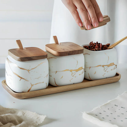 Three-piece Nordic Gold Marble Jar Set in white ceramic with wooden tray and bamboo spoons on kitchen counter