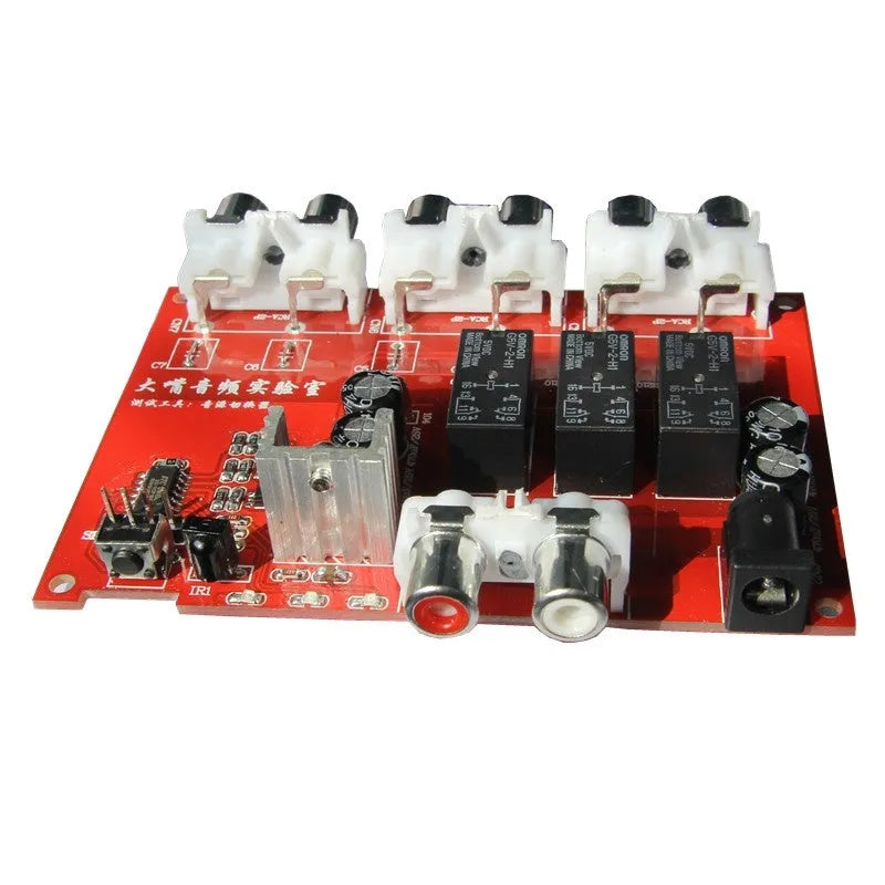 Silver aluminium audio source switch selector unit with infrared remote control on a black surface.