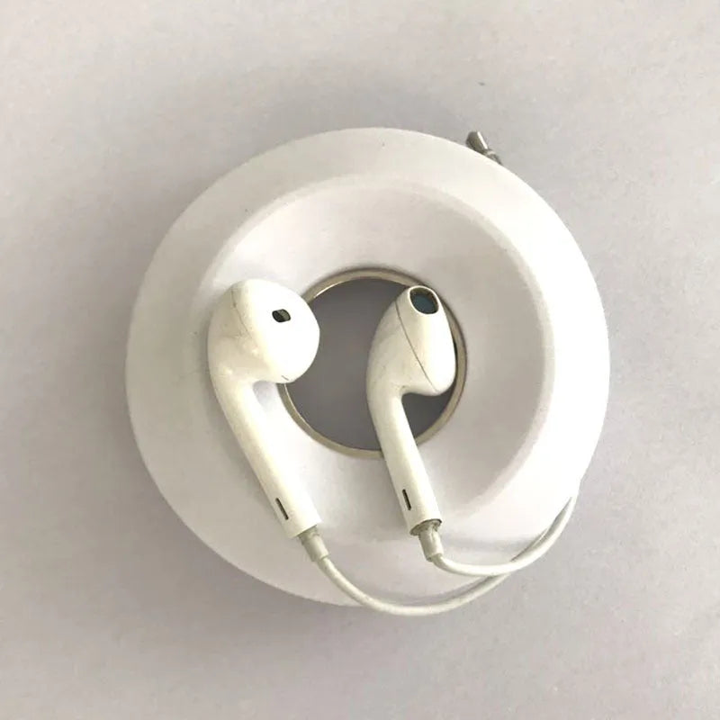 Silicone donut cord reel with magnet for organising mobile phone and headphone cables in light grey colour