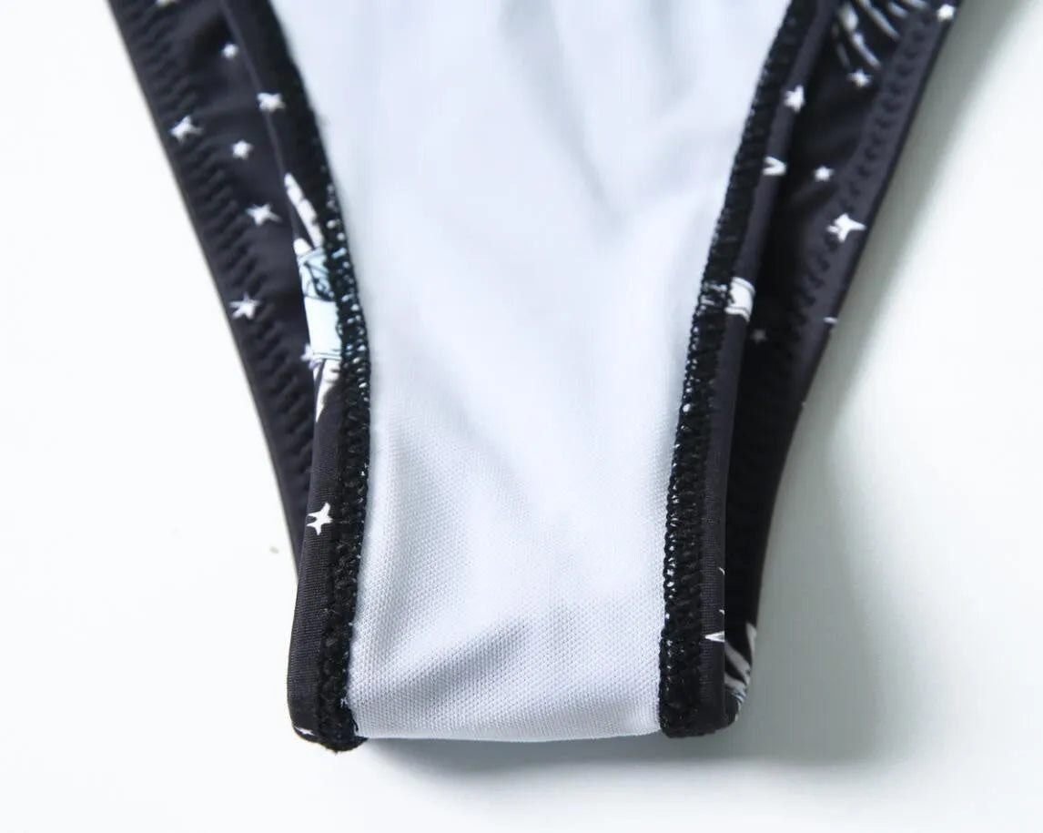 Black bikini print one-piece swimsuit for women, backless design, on a mannequin.