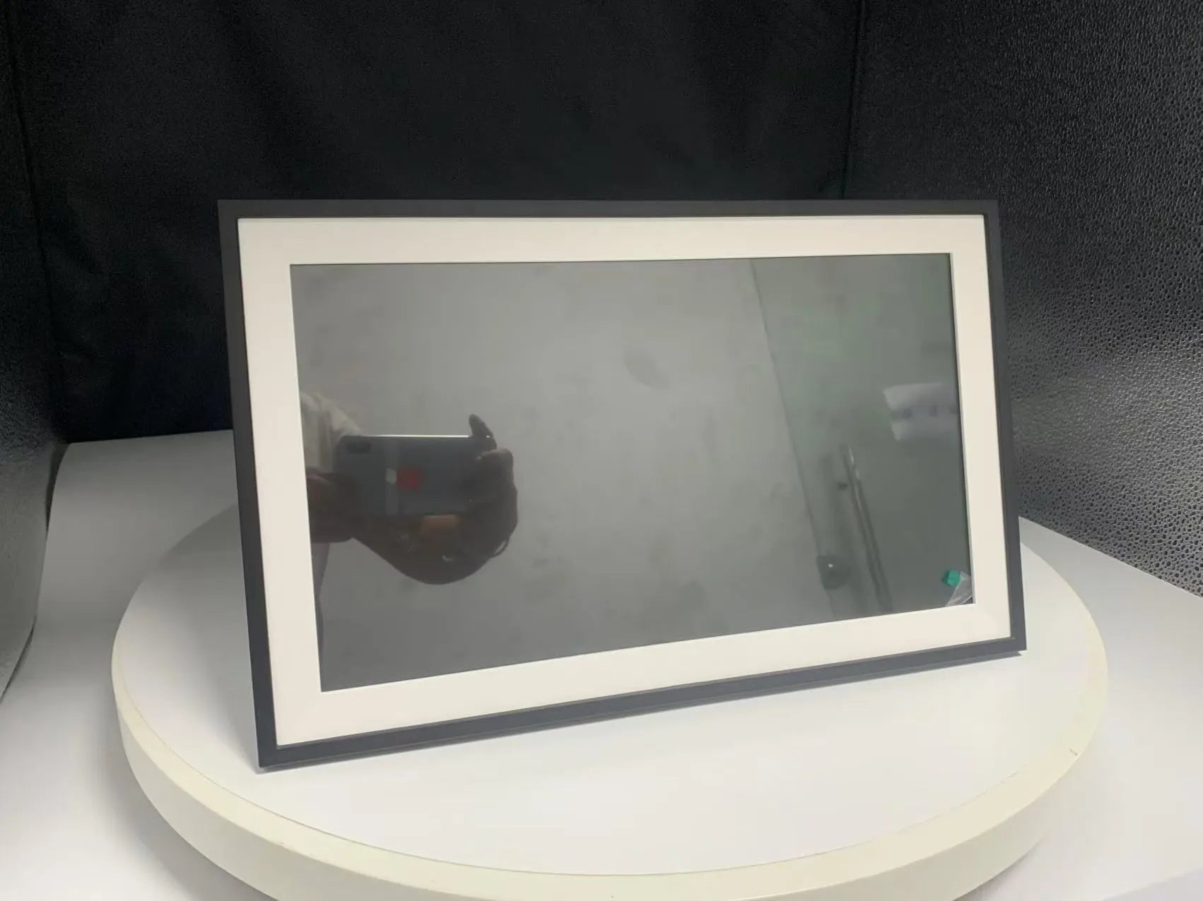 White smart digital photo frame with 15.6-inch screen on a table, showing a family photo in high definition.