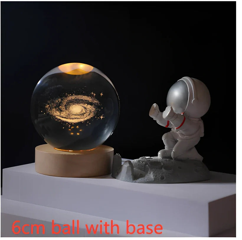 3D crystal ball night light projecting solar system pattern on wooden base with astronaut figurine