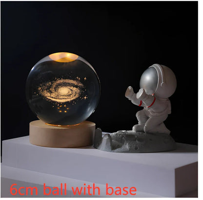 3D crystal ball night light projecting solar system pattern on wooden base with astronaut figurine