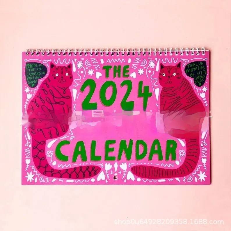 Cat-themed paper wall calendar for 2024 or 2025 year, showing monthly grid with feline artwork.