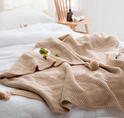 Nordic style fringed knit acrylic blanket in beige colour on a sofa