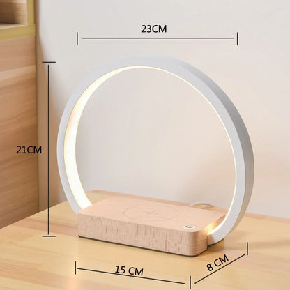 White wireless charging table lamp with metal shade and button switch on wooden surface