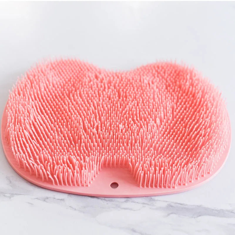 Orange non-slip massage bath brush with silicone bristles and suction cup base on shower floor