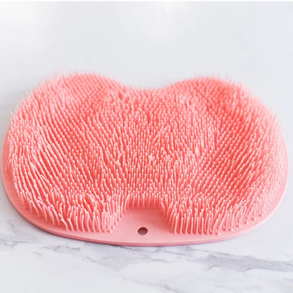 Orange non-slip massage bath brush with silicone bristles and suction cup base on shower floor