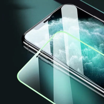 Luminous tempered glass screen protector glowing in dark next to iPhone