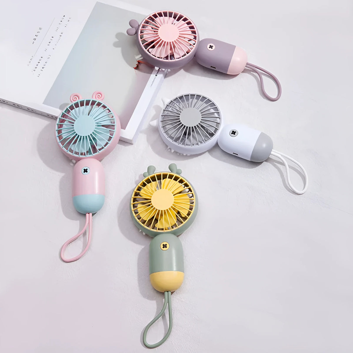 Handheld portable mini fan in green, pink, purple, or white, made from ABS and silicone with 500mAh battery