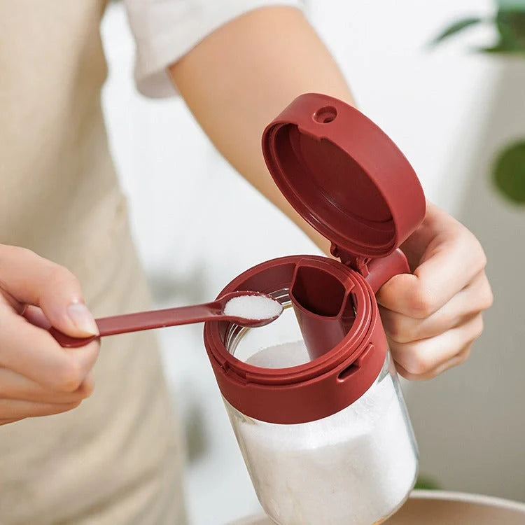 Small glass seasoning jars with lids and spoons in various colors for kitchen organization