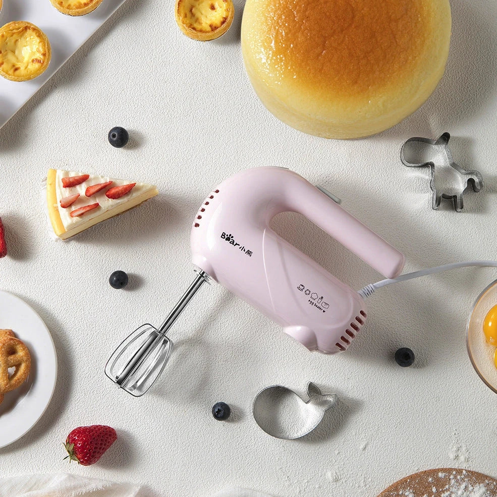 Pink electric hand whisk with stainless steel attachments for whipping eggs and cream