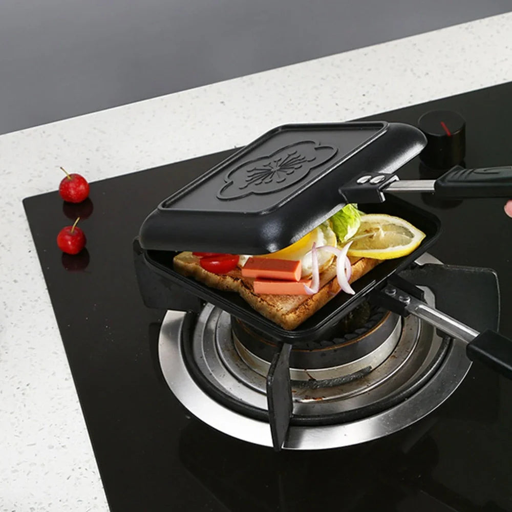 Black double-sided sandwich frying pan with heat-proof handle on stovetop