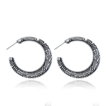 Close-up of vintage-style C-shaped alloy earrings with engraved detail, shown in bronze tone.
