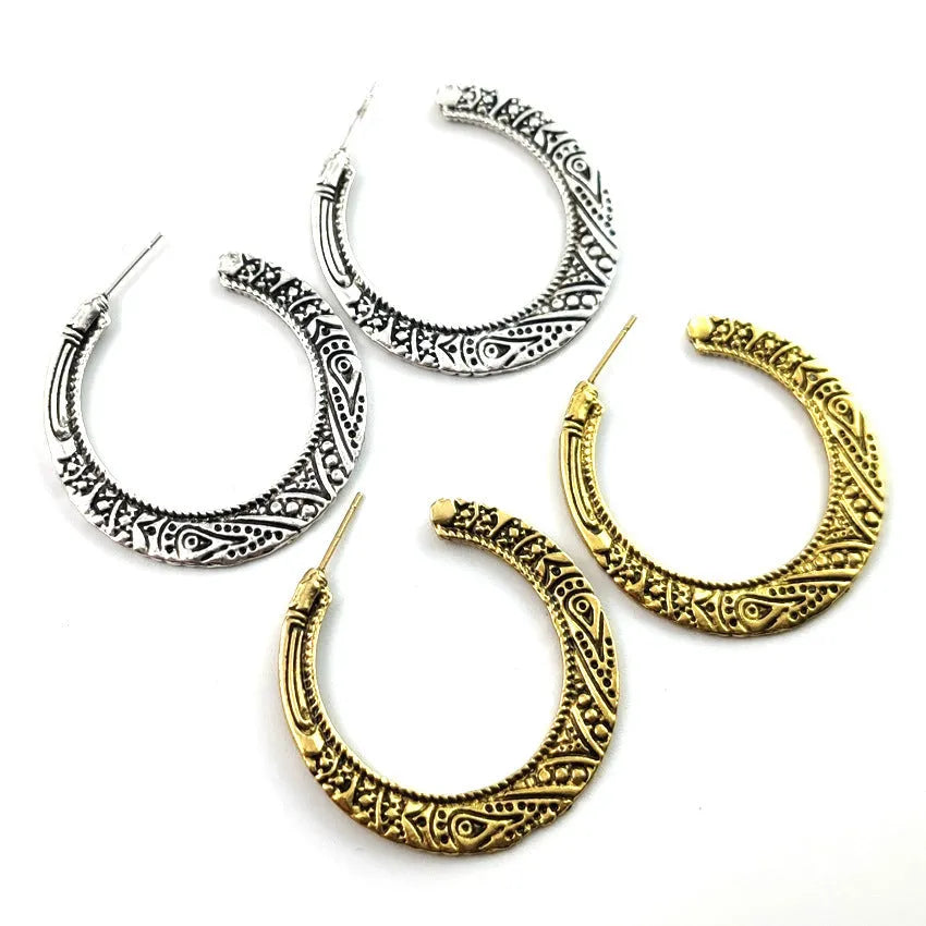 Close-up of vintage-style C-shaped alloy earrings with engraved detail, shown in bronze tone.