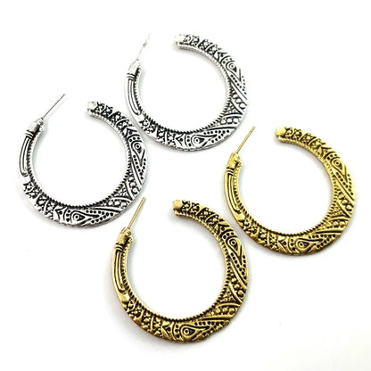 Close-up of vintage-style C-shaped alloy earrings with engraved detail, shown in bronze tone.