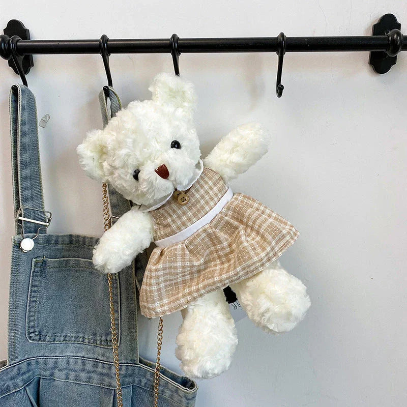 A plush teddy bear crossbody messenger bag with an adjustable shoulder strap and a zippered interior pocket for convenient storage.
