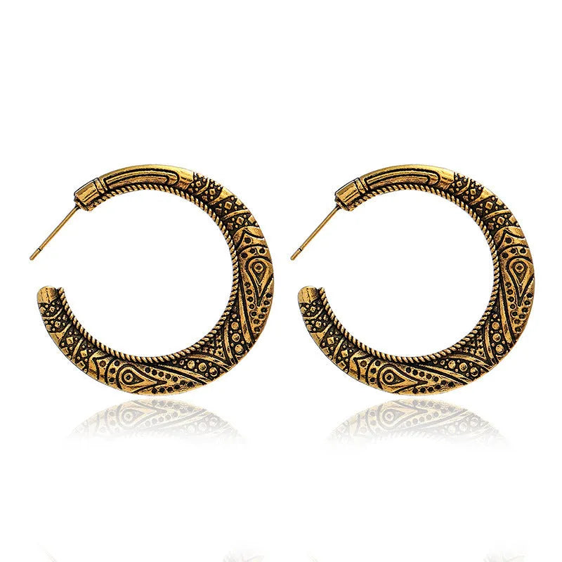 Close-up of vintage-style C-shaped alloy earrings with engraved detail, shown in bronze tone.