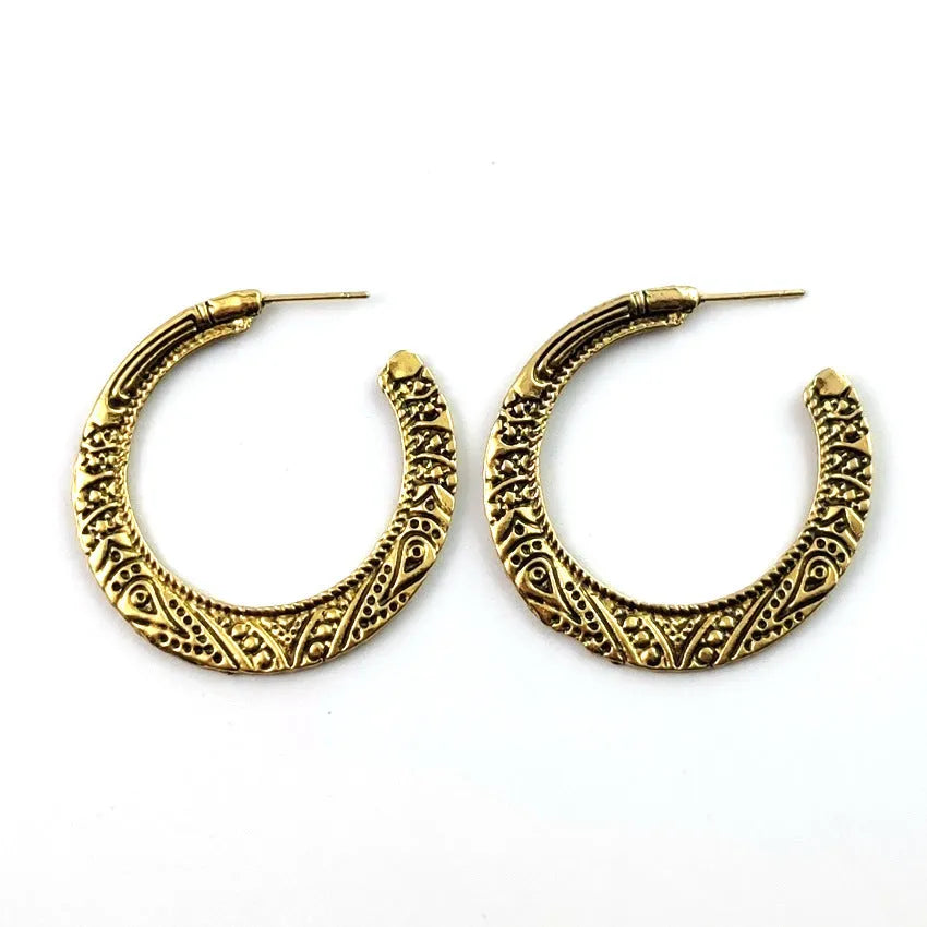 Close-up of vintage-style C-shaped alloy earrings with engraved detail, shown in bronze tone.