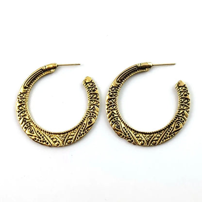 Close-up of vintage-style C-shaped alloy earrings with engraved detail, shown in bronze tone.