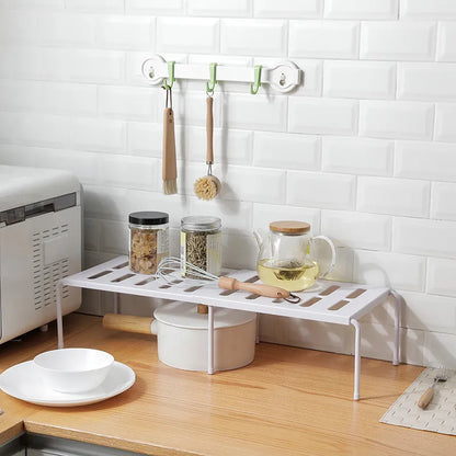 White telescopic kitchen storage rack at adjustable height on a countertop