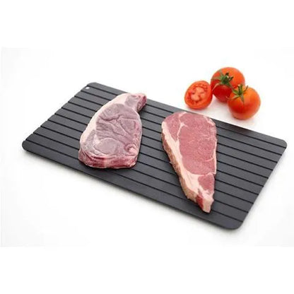 Black aluminium fast defrosting tray for kitchen use, shown thawing frozen meat.