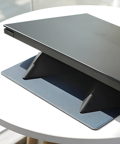 Blue or grey foldable laptop cooling stand with anti-slip surface on a desk.