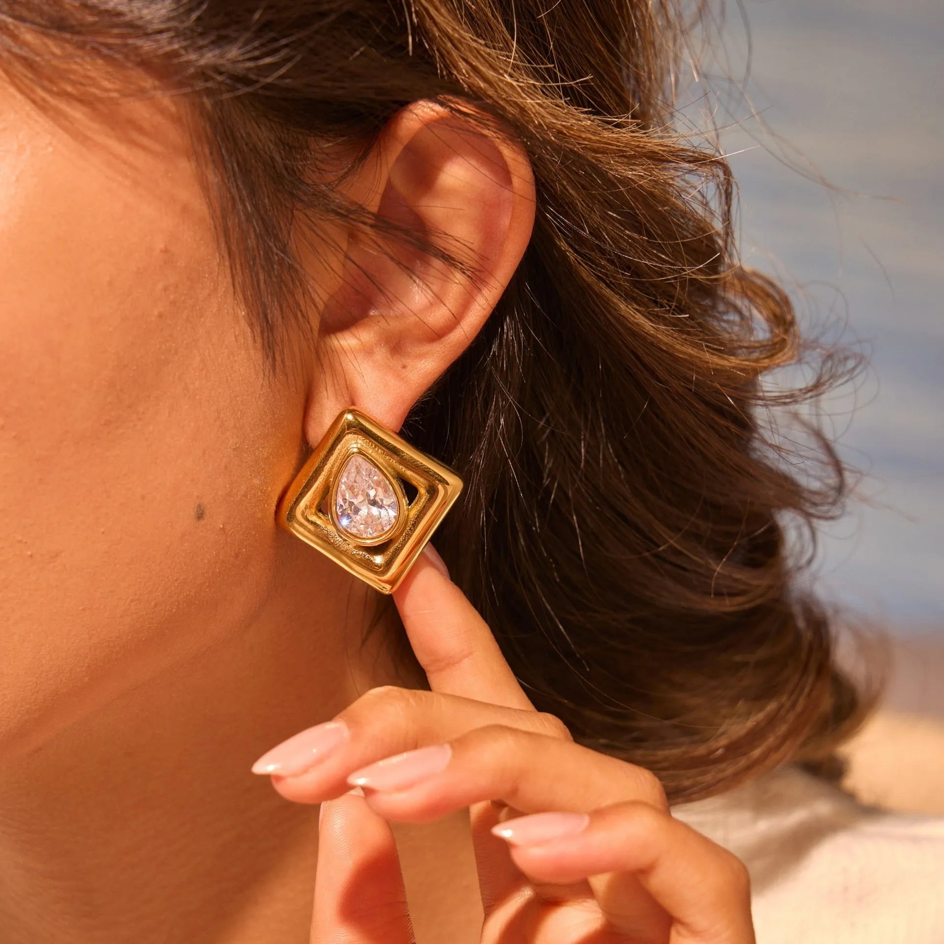 Gold geometric stud earrings for women with inlaid water drop zircon stones on a white background.
