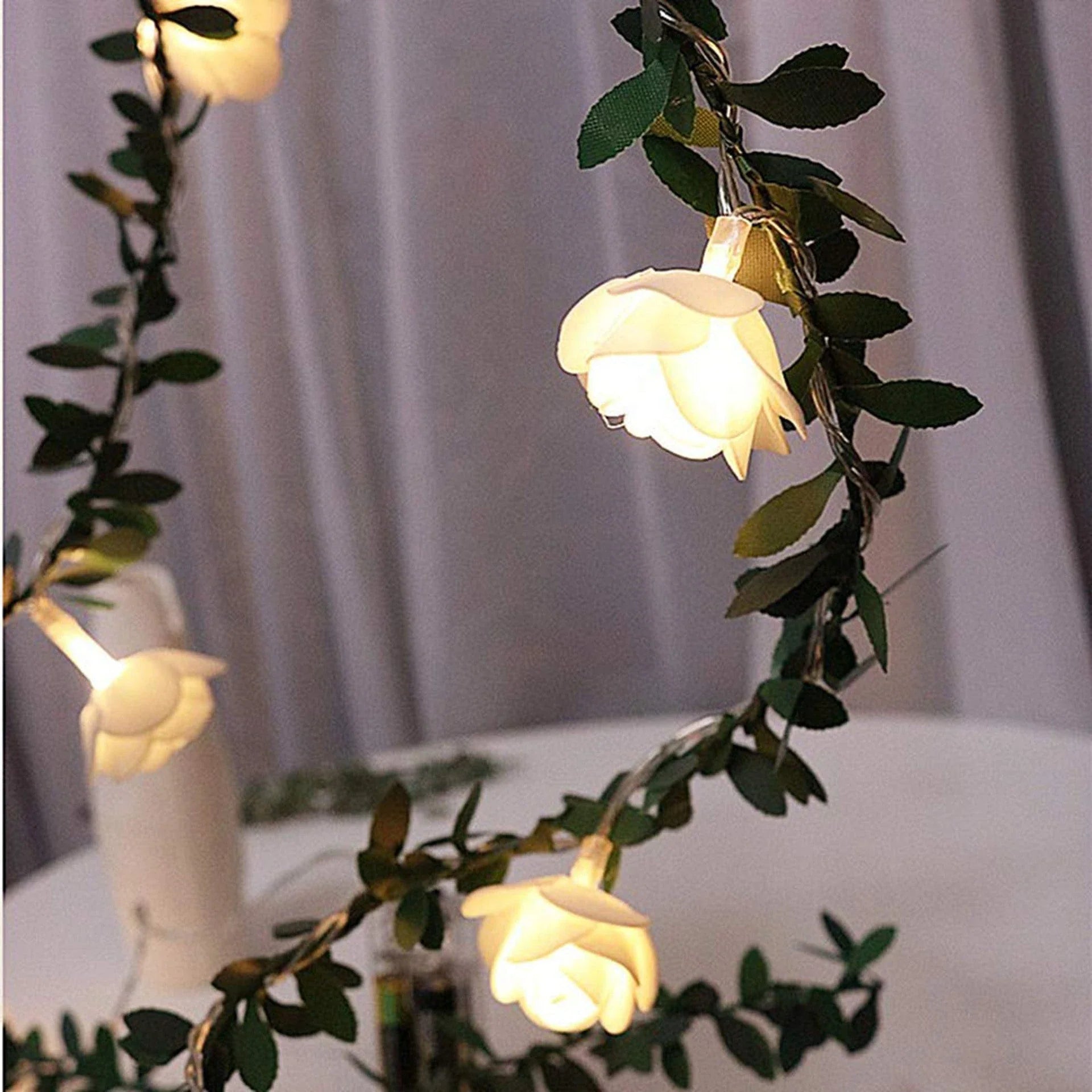 Enchanting rose vine string lights with warm white LED illumination and natural green leaves and rose buds