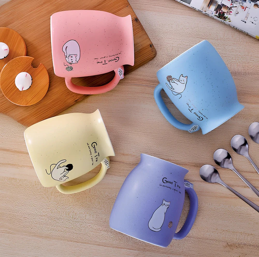 Pink ceramic mug with cartoon cat design, wooden lid, and stainless steel spoon on table