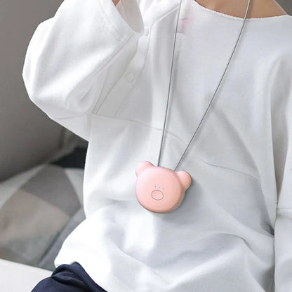 Pink wearable USB air purifier necklace on a table with USB cable, showing compact size.