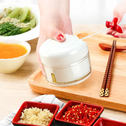 White manual food chopper with stainless steel blades on a kitchen countertop.